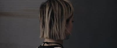 a woman with blonde hair standing in front of a wall