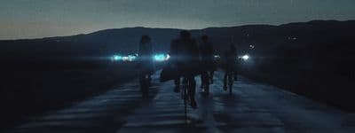 a group of people riding bikes down a road at night