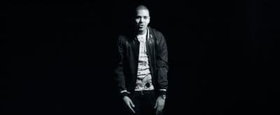a man standing in the dark with his hands in his pockets