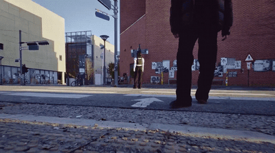 a man walking down a street next to a tall building