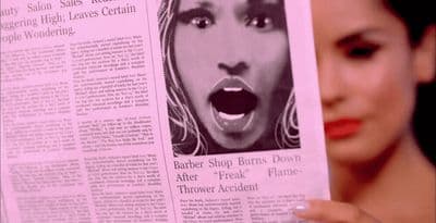 a woman holding up a newspaper with a picture of a woman's face on