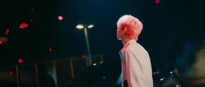 a man with pink hair standing in front of a car