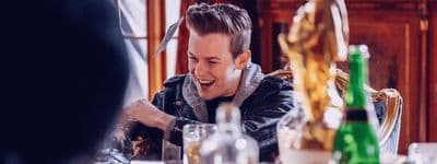 a man laughing while sitting at a table