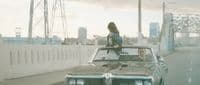 a woman standing on the hood of a car