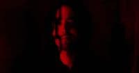 a man with long hair standing in a dark room