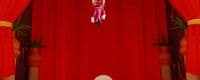 a cartoon character is suspended from a red curtain