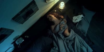 a woman laying on a bed in a dark room