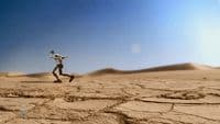 a man running across a desert covered in sand