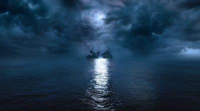 a boat floating on a body of water under a cloudy sky