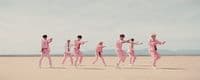 a group of people in pink outfits running across a desert