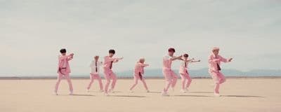 a group of people in pink outfits running across a desert