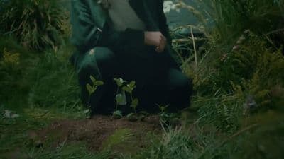 a woman sitting on the ground in the grass