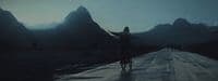 a person riding a bike on a road with mountains in the background