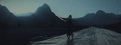 a person riding a bike on a road with mountains in the background