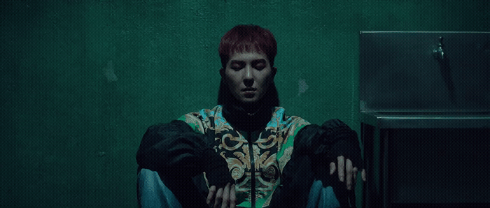 a man with red hair sitting in front of a green wall