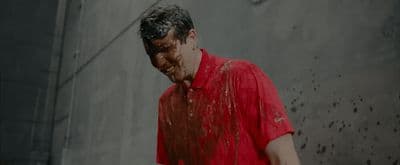 a man in a red shirt standing in the rain