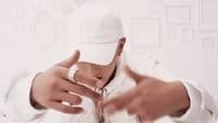 a man wearing a white hat making a hand gesture