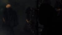 a man in a black coat walking down a dark hallway