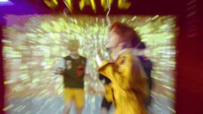 a blurry photo of two people standing in front of a television screen