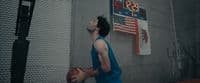 a man holding a basketball in front of a scoreboard