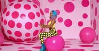 a woman sitting on top of a pink ball