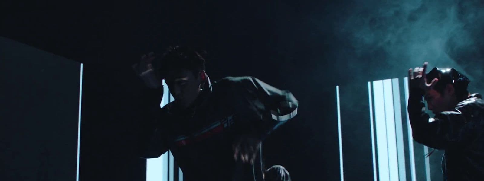 a man standing next to another man in a dark room
