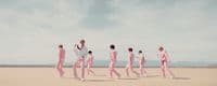 a group of men in pink suits walking across a desert