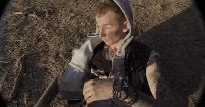 a man in a hoodie sitting on the ground