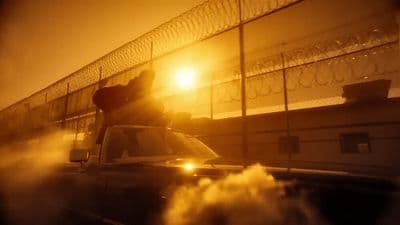 a car driving down a road next to a fence