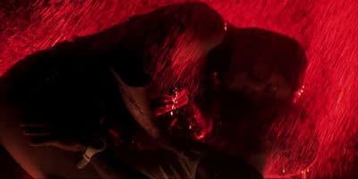 a person standing under a red light in the rain