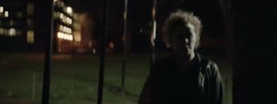 a man standing in front of a fence at night