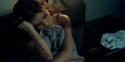 a woman sitting on a couch with a tattoo on her arm