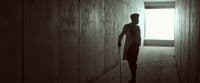 a man walking down a hallway with a cane