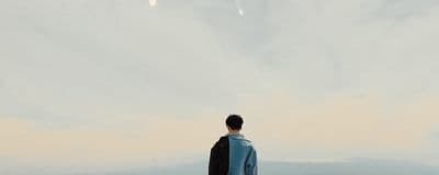 a man standing on top of a hill under a cloudy sky