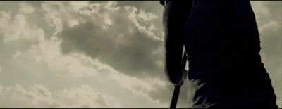 a silhouette of a man with a cane against a cloudy sky