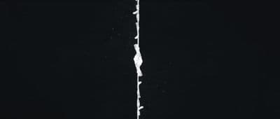a black and white photo of a crack in a wall