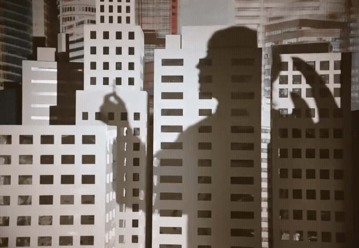 a shadow of a man standing in front of tall buildings