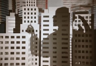 a shadow of a man standing in front of tall buildings