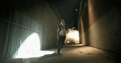 a woman is walking down a dark alley way