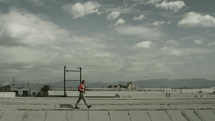 a man walking across a roof in the middle of the day