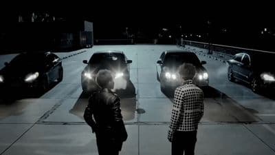 a couple of men standing next to each other in front of a car