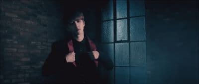 a young man in a dark room holding a cell phone