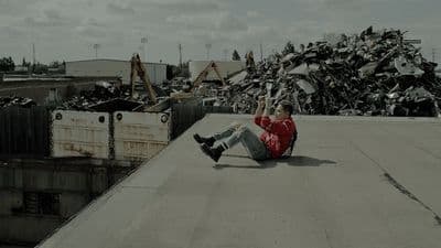 a man sitting on top of a roof next to a pile of junk