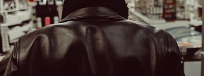a man in a leather jacket walking down a street