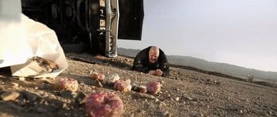 a man laying on the ground next to a truck
