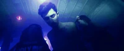 a man standing in a dark room next to a woman