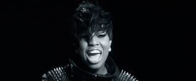 a woman in a leather jacket singing into a microphone