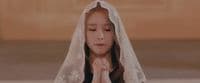 a woman wearing a veil and praying with her hands together