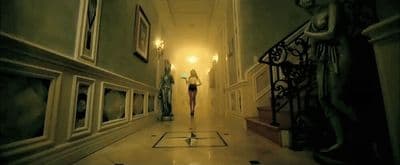 a woman is walking down a long hallway