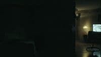 a dark room with a chair and a television